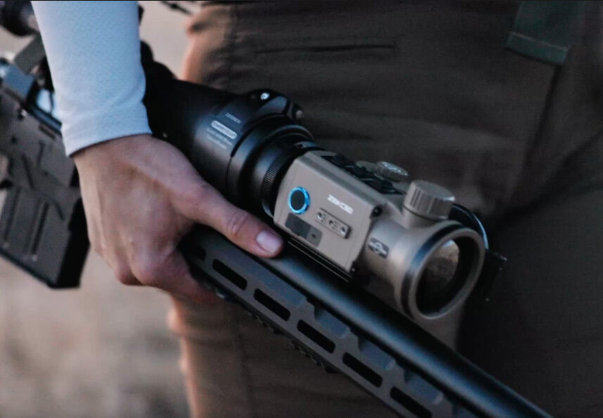 Nahaufnahme einer Person, die ein Gewehr mit einem digitalen Zielfernrohr hält