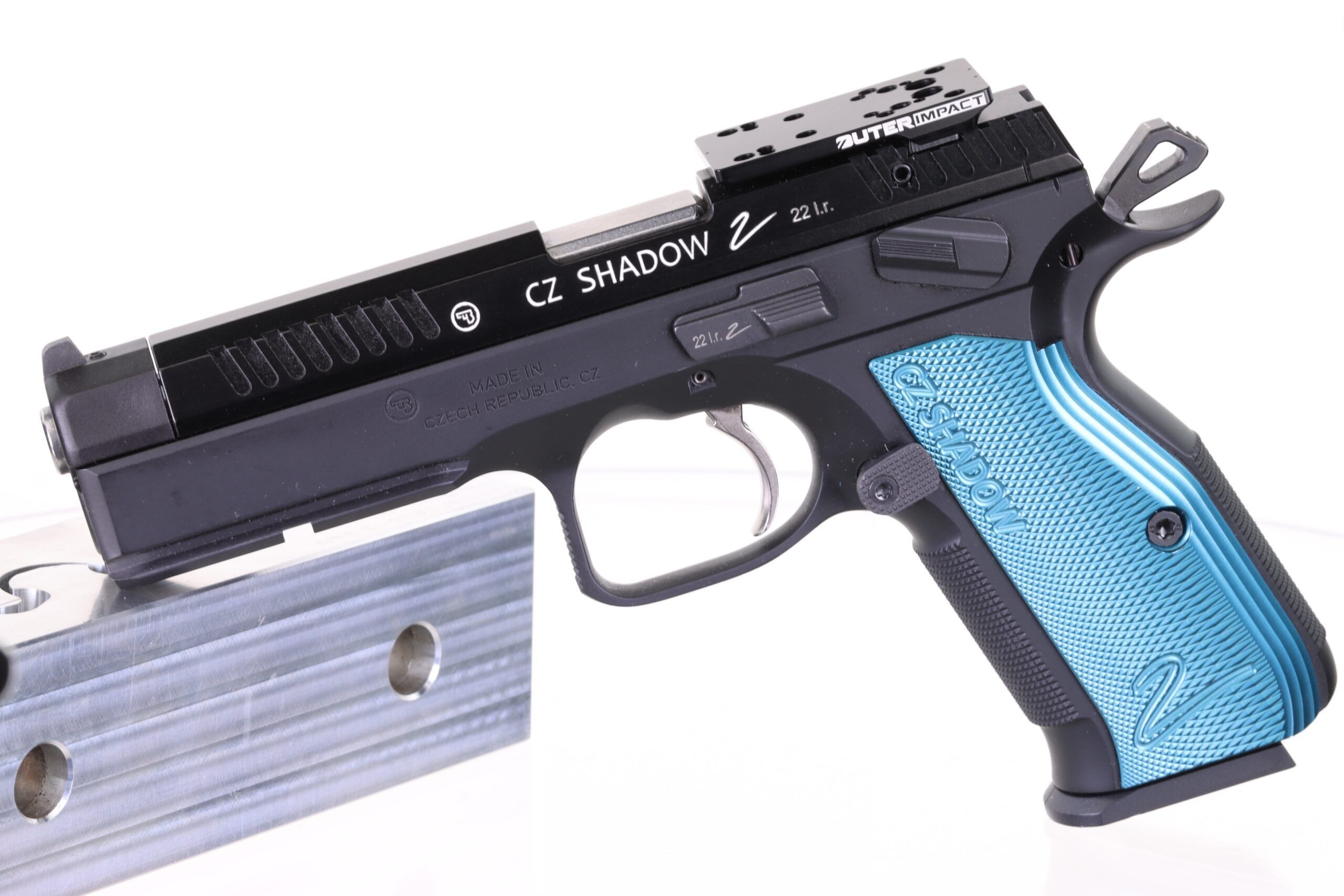 Schwarze und blaue CZ Shadow 2 Pistole mit geöffneter Kammeransicht, positioniert auf einem metallischen Standfuß